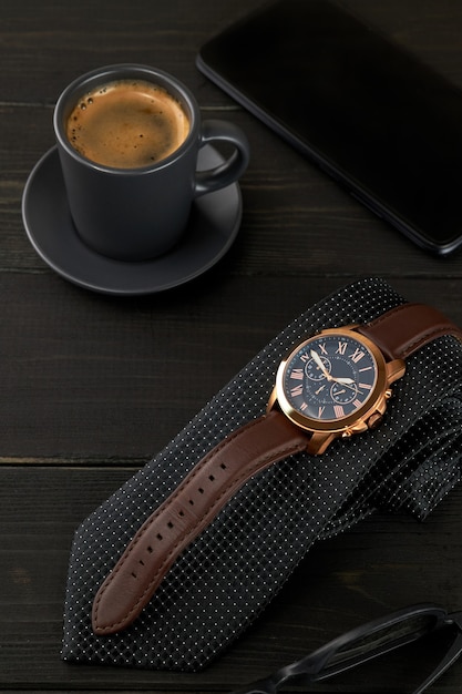 freepicdownloader.com men s wrist watch black tie cup hot coffee smartphone wooden table normal